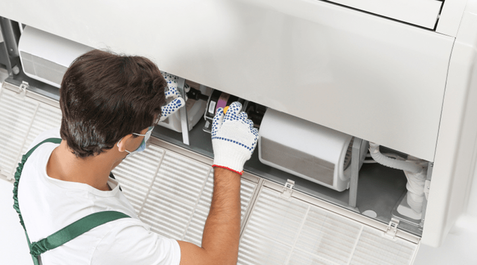 Male Technician fixing Air Conditioner — Commercial HVAC Cleaners in South East Queensland